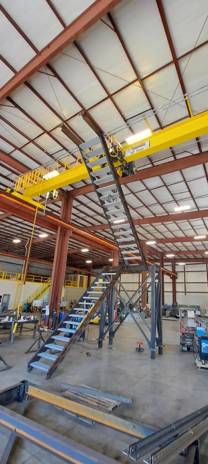 Custom fabricated industrial stair and elevated platform assembly in a fabrication shop